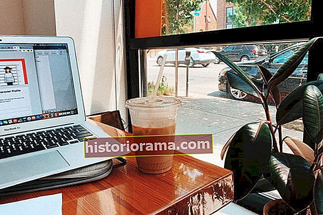 person sidder med computeren i kaffebaren med iskaffe